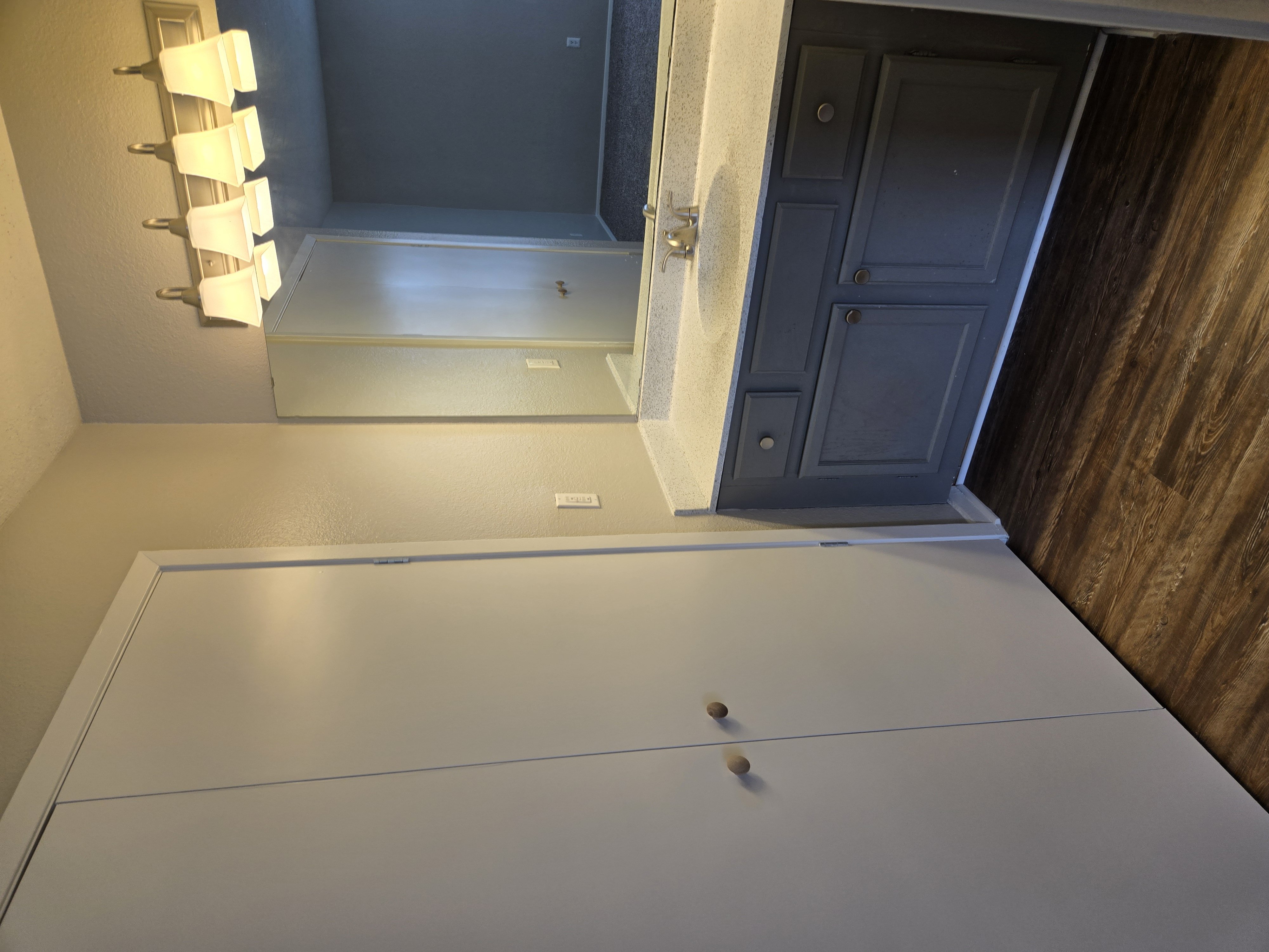A white countertop with a sink and a cabinet door.